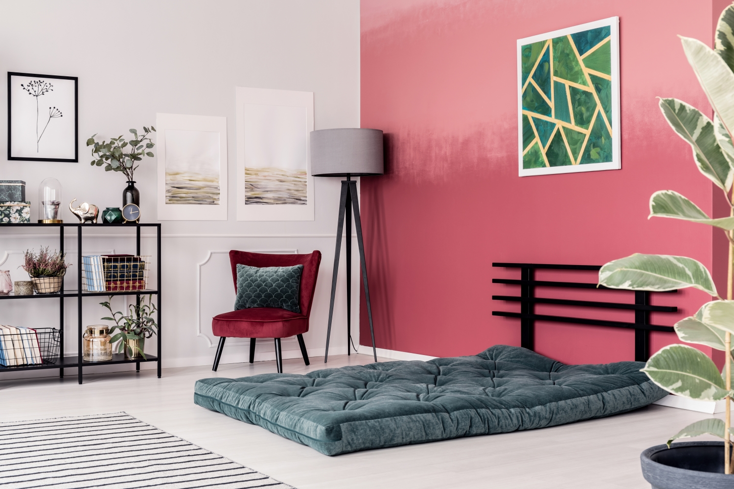materac na podłodze w pokoju z różową ścianę, fotelem, lampą i obrazem