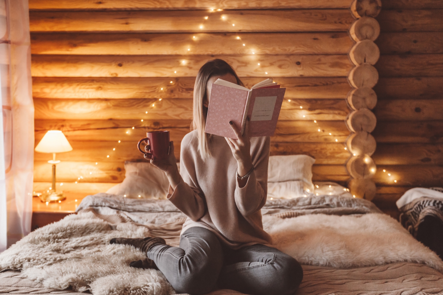 8 dobrych nawyków przed snem, kobieta siedząca na łóżku i czytająca książka